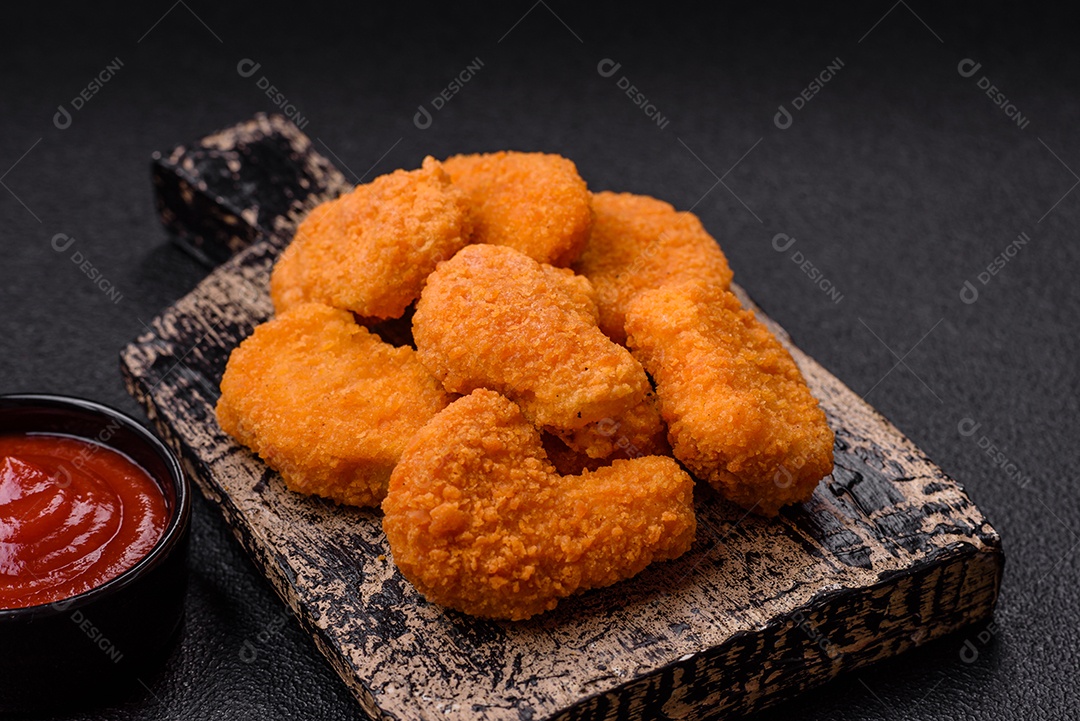 Deliciosos nuggets de frango crocantes frescos em um fundo escuro de concreto. Alimentos não saudáveis, fast food