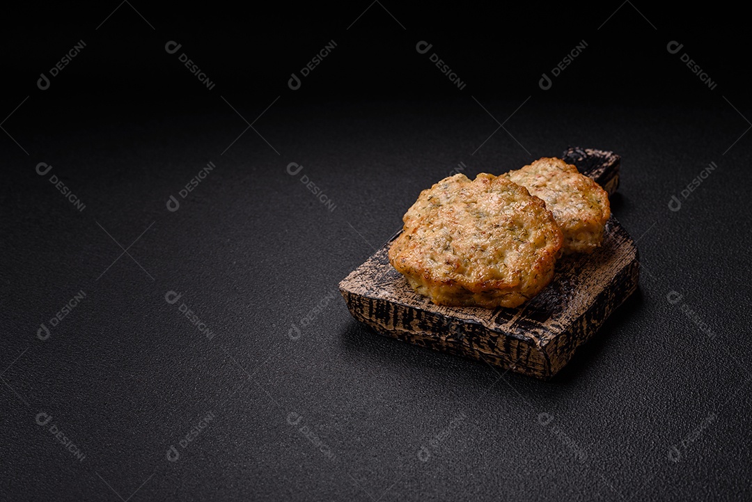 Deliciosas costeletas de frango picado frito com sal, especiarias e ervas sobre um fundo escuro de concreto