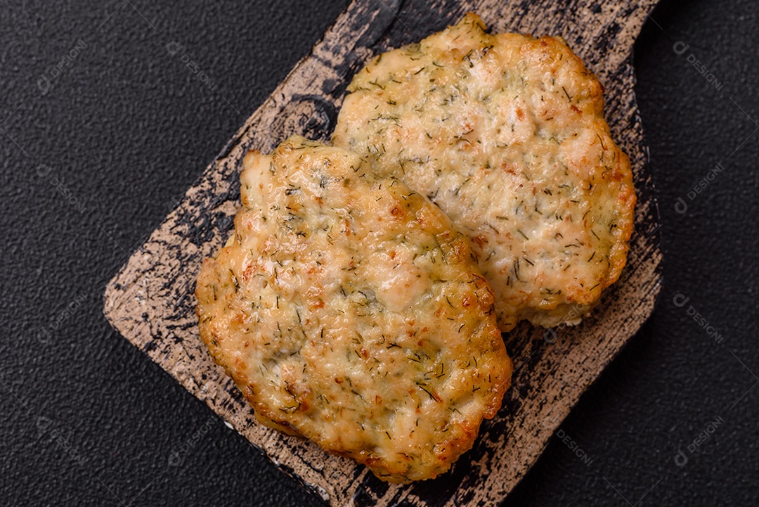 Deliciosas costeletas de frango picado frito com sal, especiarias e ervas sobre um fundo escuro de concreto