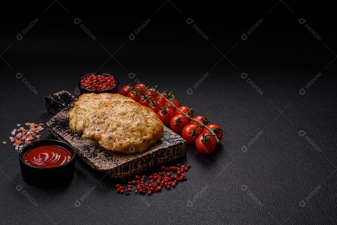 Deliciosas costeletas de frango picado frito com sal, especiarias e ervas sobre um fundo escuro de concreto