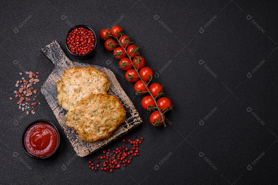 Deliciosas costeletas de frango picado frito com sal, especiarias e ervas sobre um fundo escuro de concreto