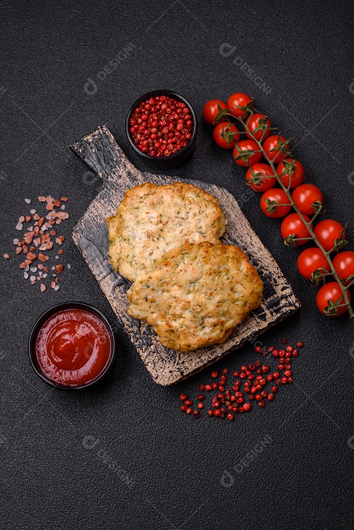 Deliciosas costeletas de frango picado frito com sal, especiarias e ervas sobre um fundo escuro de concreto