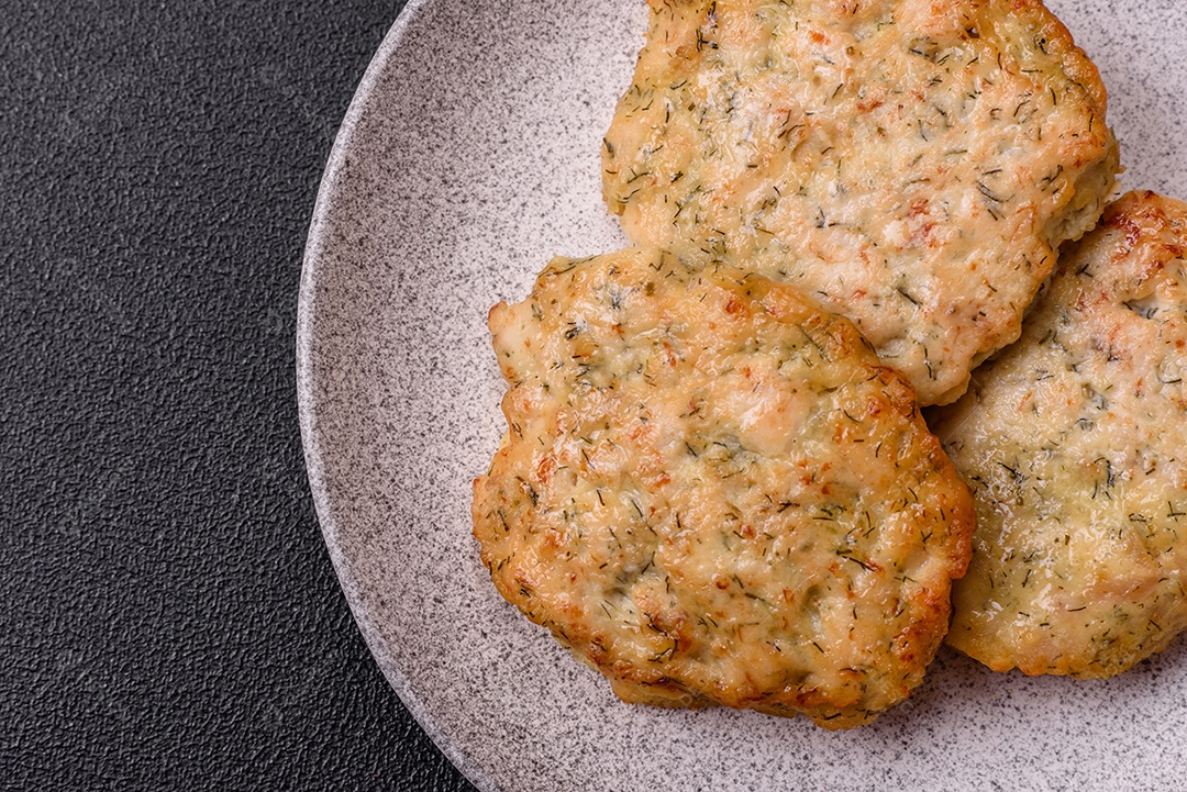 Deliciosas costeletas de frango picado frito com sal, especiarias e ervas sobre um fundo escuro de concreto