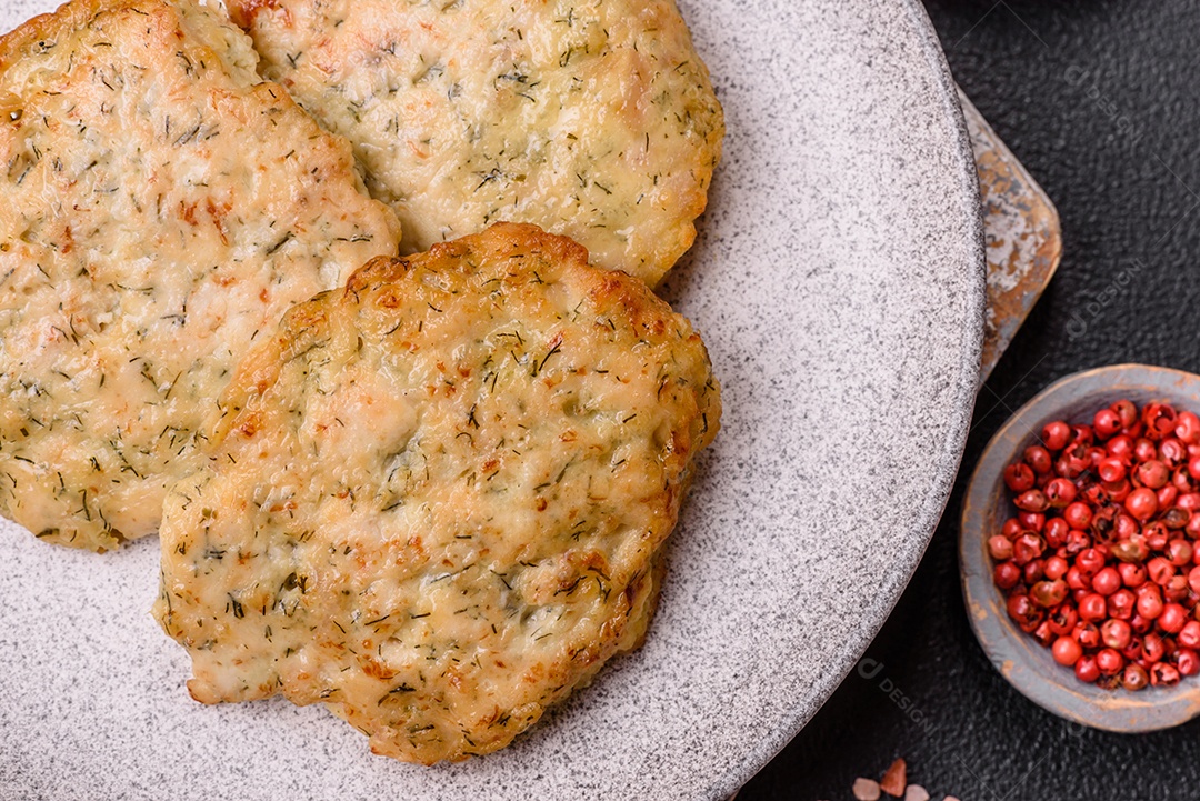 Deliciosas costeletas de frango picado frito com sal, especiarias e ervas sobre um fundo escuro de concreto