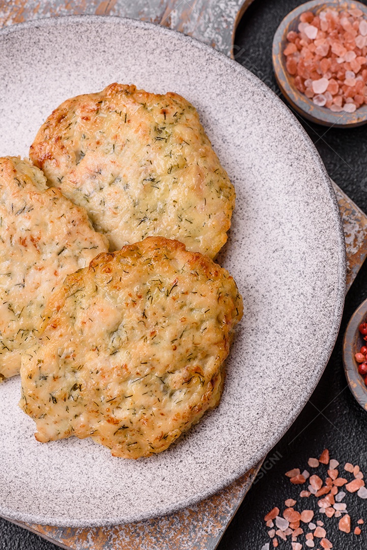 Deliciosas costeletas de frango picado frito com sal, especiarias e ervas sobre um fundo escuro de concreto