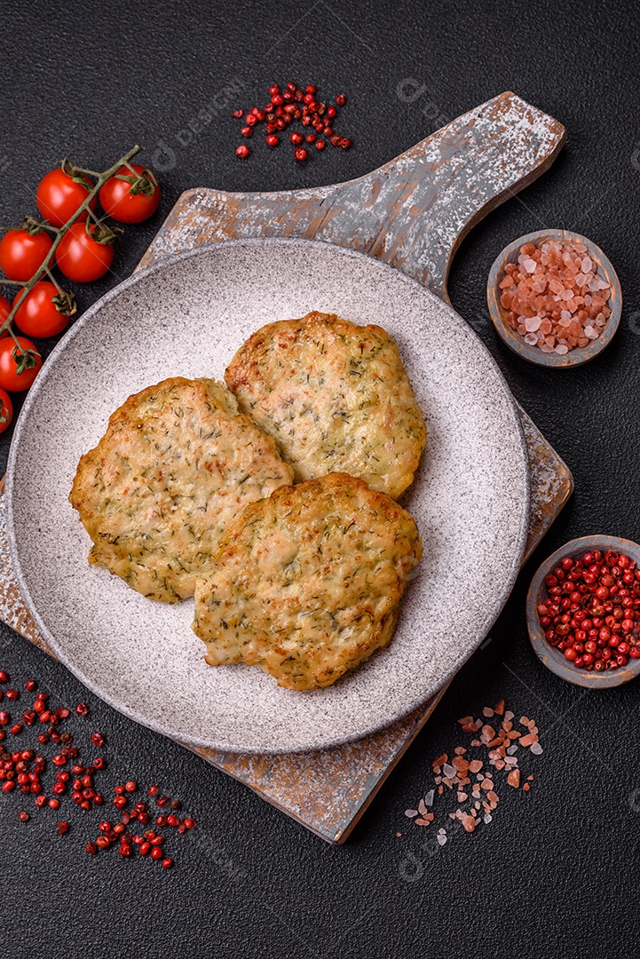 Deliciosas costeletas de frango picado frito com sal, especiarias e ervas sobre um fundo escuro de concreto