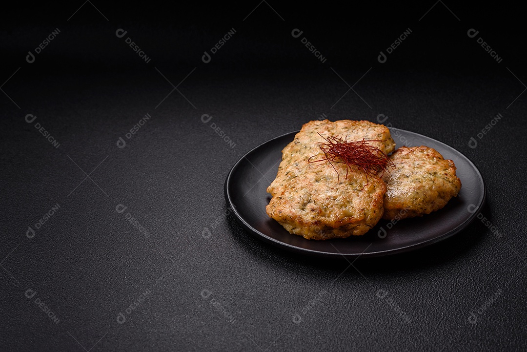 Deliciosas costeletas de frango picado frito com sal, especiarias e ervas sobre um fundo escuro de concreto