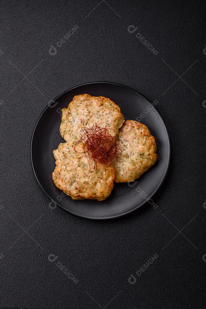 Deliciosas costeletas de frango picado frito com sal, especiarias e ervas sobre um fundo escuro de concreto