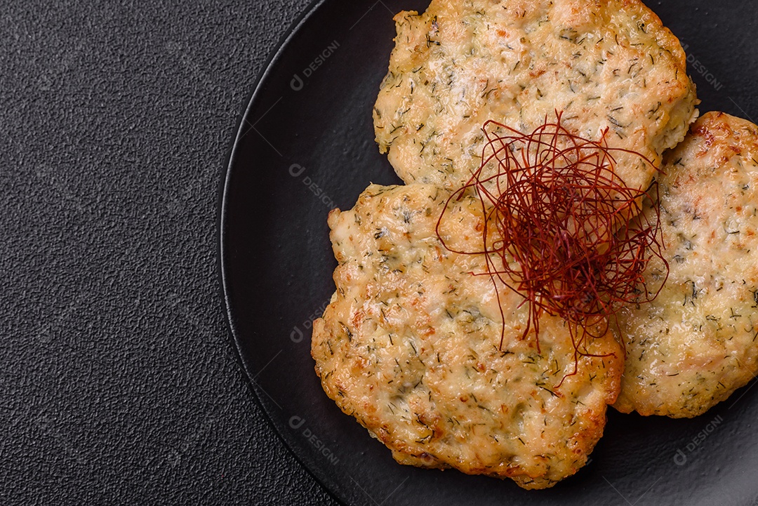 Deliciosas costeletas de frango picado frito com sal, especiarias e ervas sobre um fundo escuro de concreto