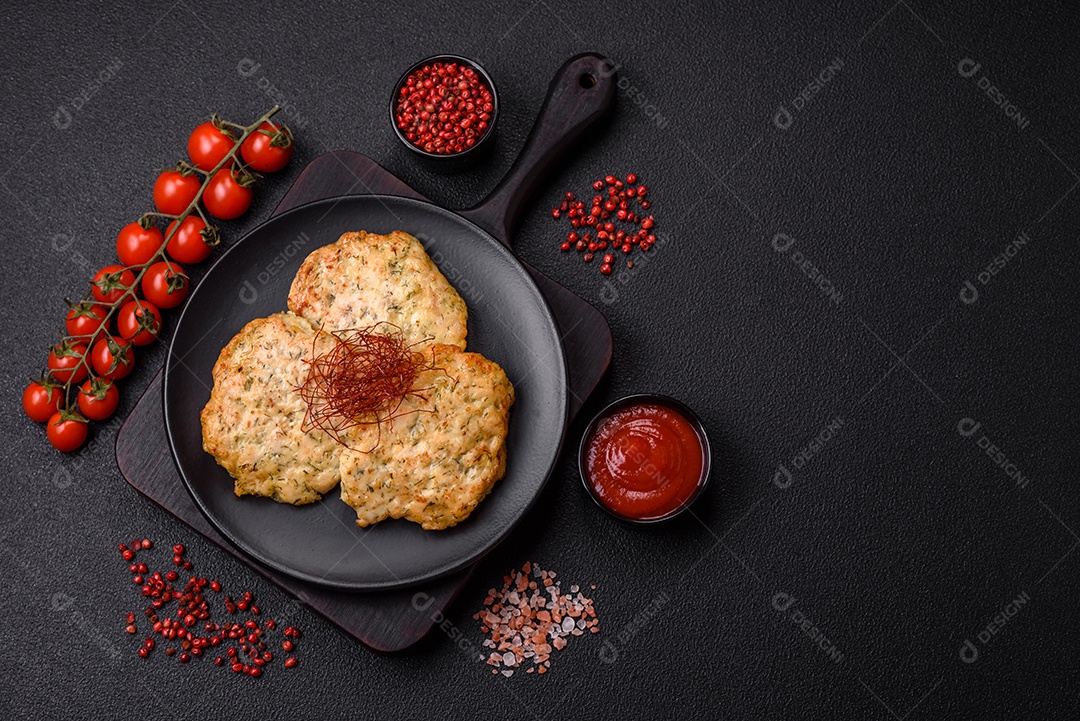 Deliciosas costeletas de frango picado frito com sal, especiarias e ervas sobre um fundo escuro de concreto