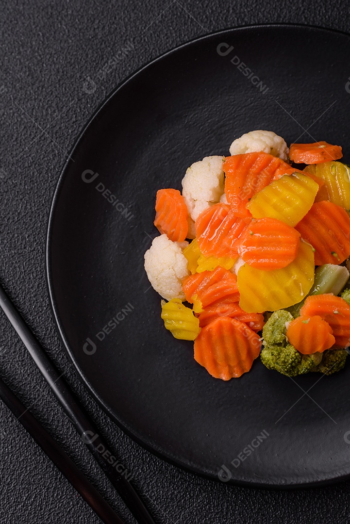 Deliciosos legumes frescos, brócolis, couve-flor, cenouras cozidas no vapor com sal, especiarias e ervas sobre fundo liso