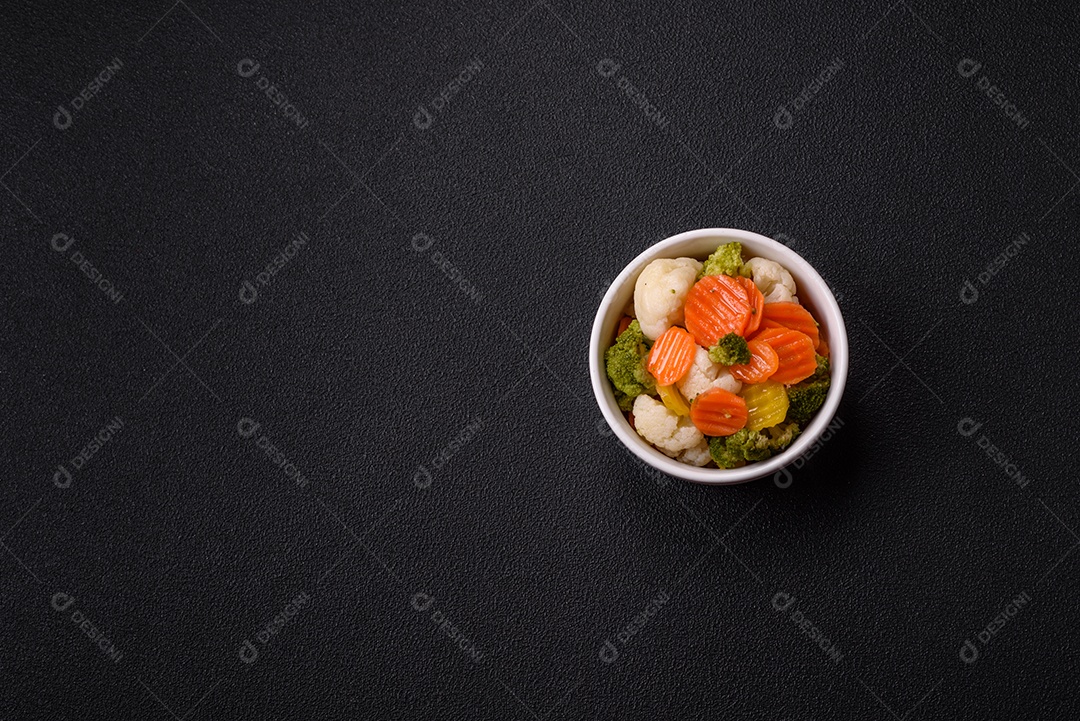 Deliciosos legumes frescos, brócolis, couve-flor, cenouras cozidas no vapor com sal, especiarias e ervas sobre fundo liso