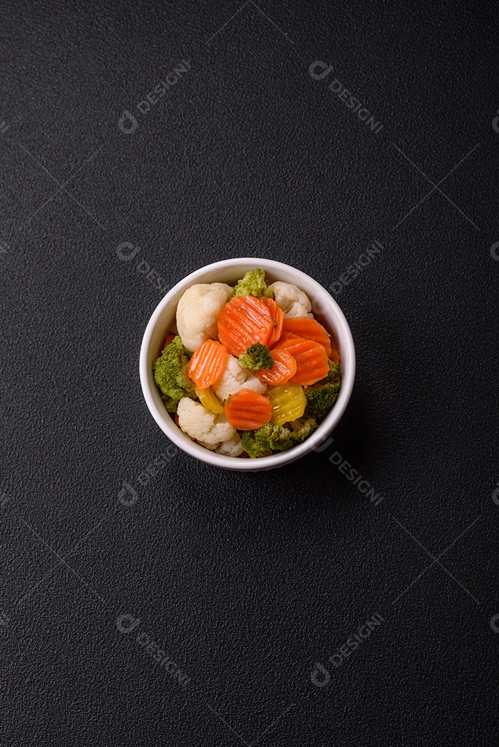 Deliciosos legumes frescos, brócolis, couve-flor, cenouras cozidas no vapor com sal, especiarias e ervas sobre fundo liso