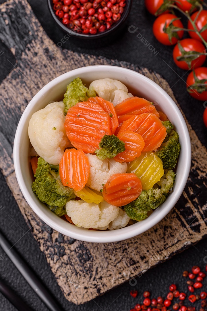 Deliciosos legumes frescos, brócolis, couve-flor, cenouras cozidas no vapor com sal, especiarias e ervas sobre fundo liso