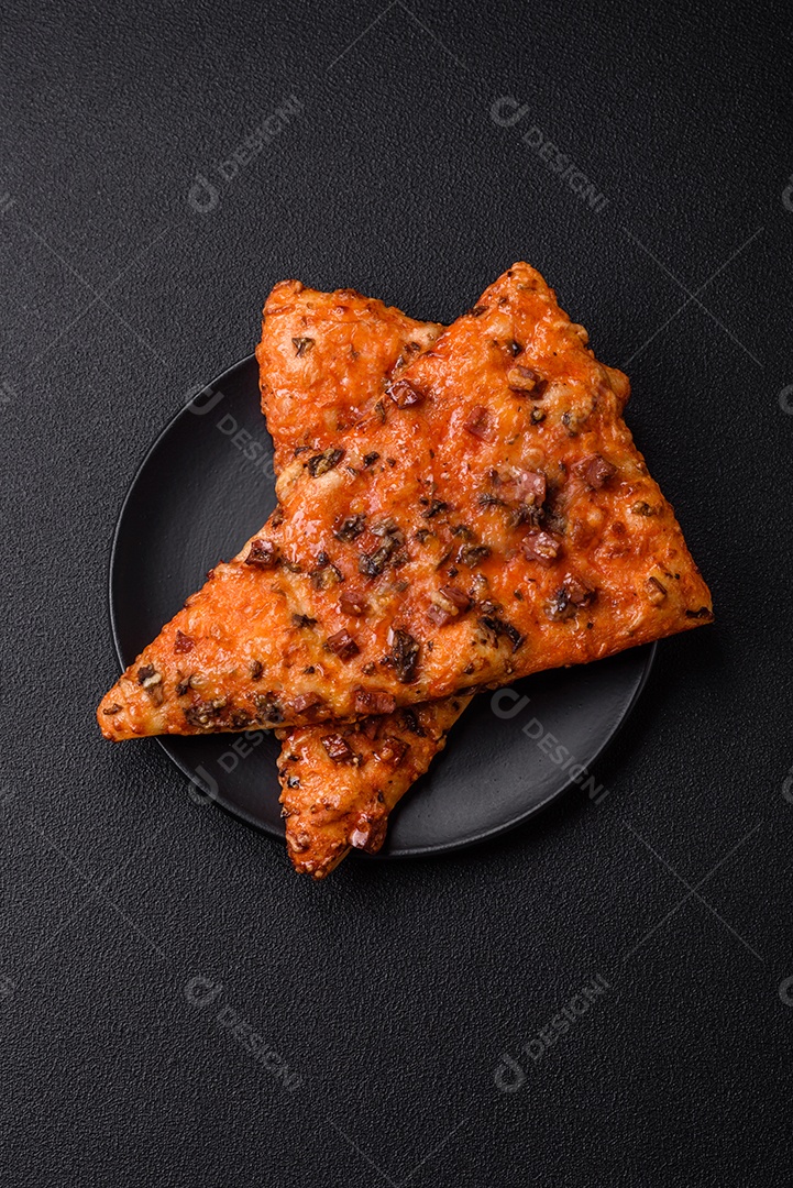 Fatias de deliciosa pizza de rua com salsicha, cogumelos, tomate e queijo com sal e especiarias sobre um fundo escuro de concreto