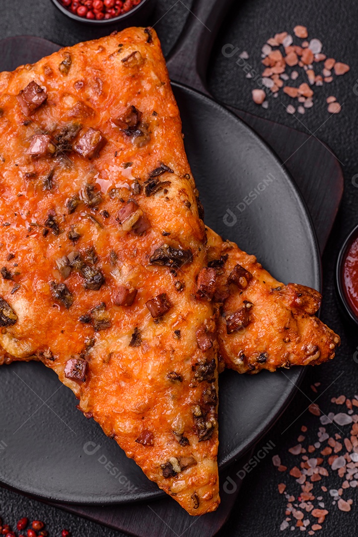 Fatias de deliciosa pizza de rua com salsicha, cogumelos, tomate e queijo com sal e especiarias sobre um fundo escuro de concreto