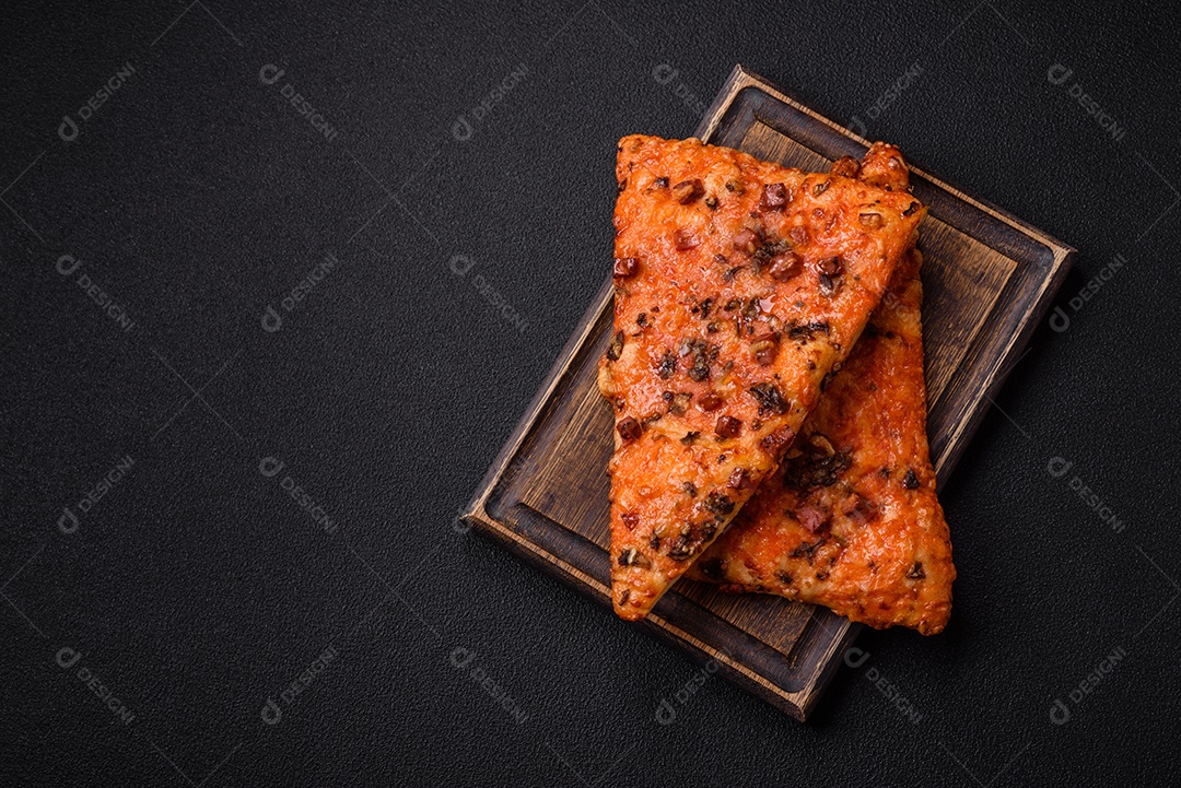 Fatias de deliciosa pizza de rua com salsicha, cogumelos, tomate e queijo com sal e especiarias sobre um fundo escuro de concreto