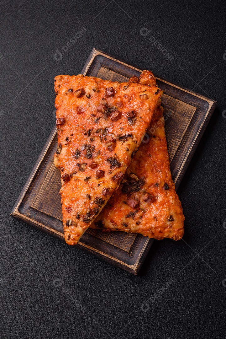 Fatias de deliciosa pizza de rua com salsicha, cogumelos, tomate e queijo com sal e especiarias sobre um fundo escuro de concreto