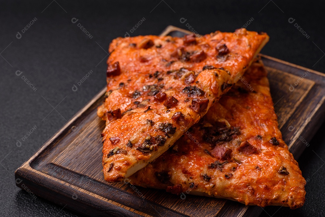 Fatias de deliciosa pizza de rua com salsicha, cogumelos, tomate e queijo com sal e especiarias sobre um fundo escuro de concreto