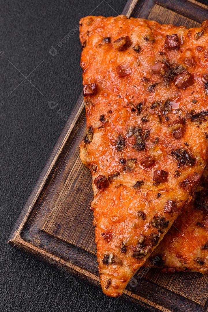 Fatias de deliciosa pizza de rua com salsicha, cogumelos, tomate e queijo com sal e especiarias sobre um fundo escuro de concreto