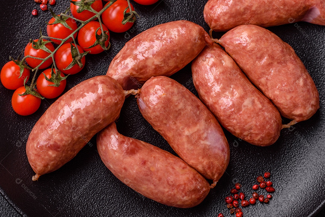 Frango assado ou salsichas de porco, sal, especiarias e ervas sobre um fundo escuro de concreto