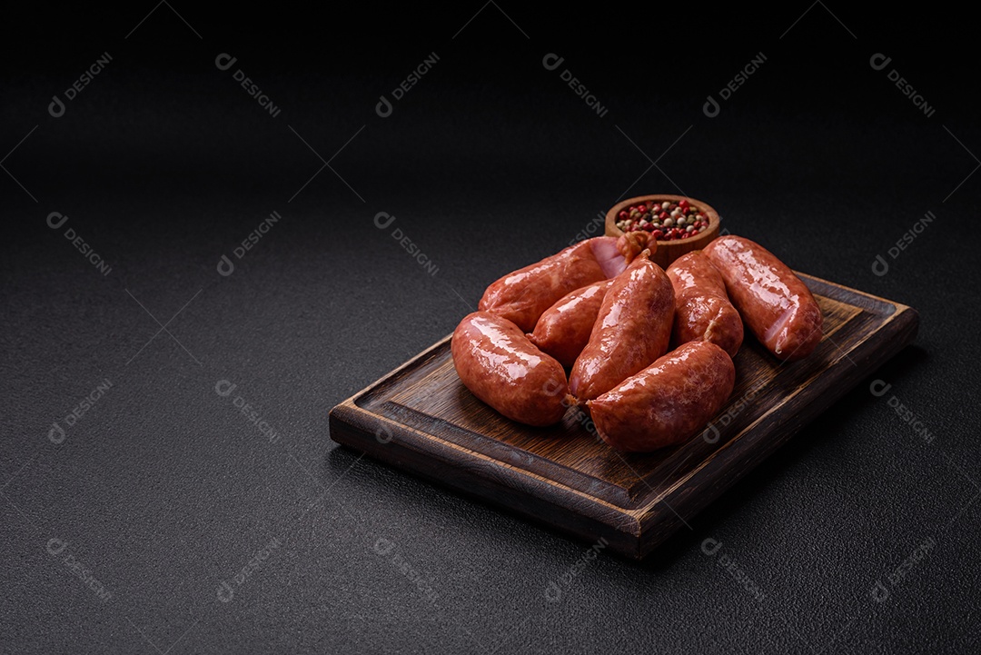 Frango assado ou salsichas de porco, sal, especiarias e ervas sobre um fundo escuro de concreto