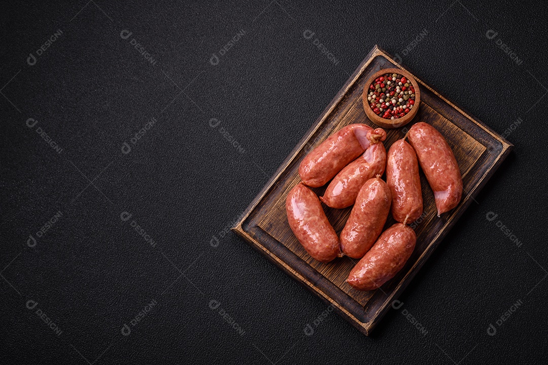 Frango assado ou salsichas de porco, sal, especiarias e ervas sobre um fundo escuro de concreto