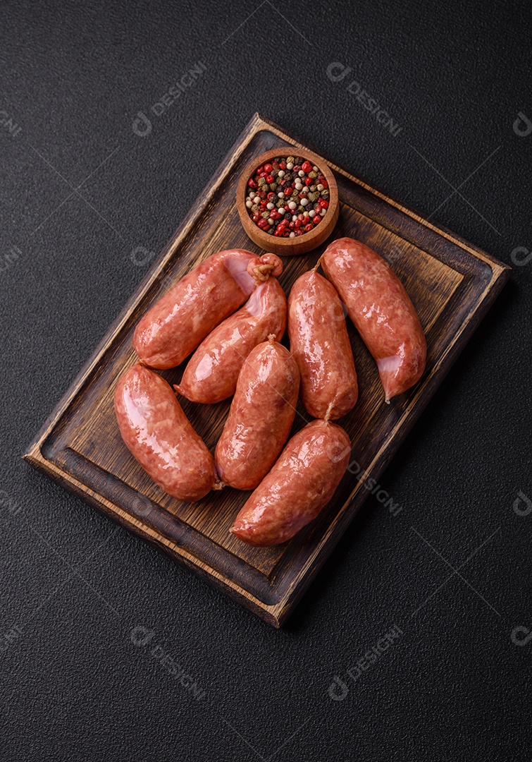 Frango assado ou salsichas de porco, sal, especiarias e ervas sobre um fundo escuro de concreto