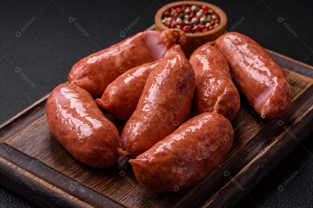 Frango assado ou salsichas de porco, sal, especiarias e ervas sobre um fundo escuro de concreto