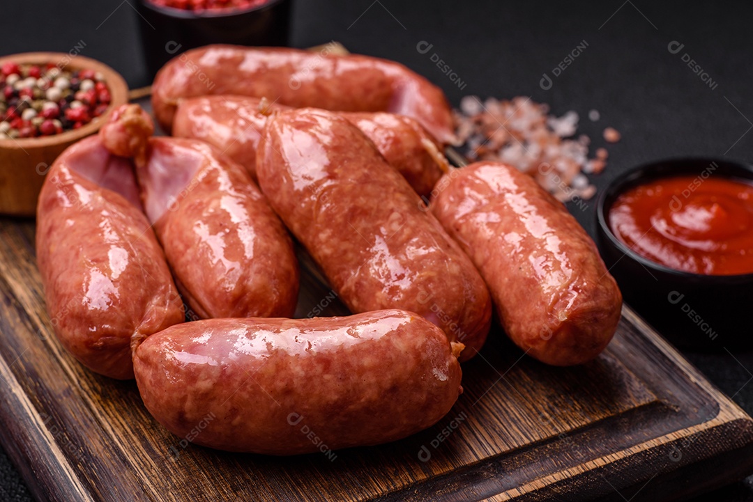 Frango assado ou salsichas de porco, sal, especiarias e ervas sobre um fundo escuro de concreto