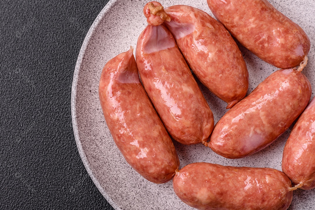 Frango assado ou salsichas de porco, sal, especiarias e ervas sobre um fundo escuro de concreto