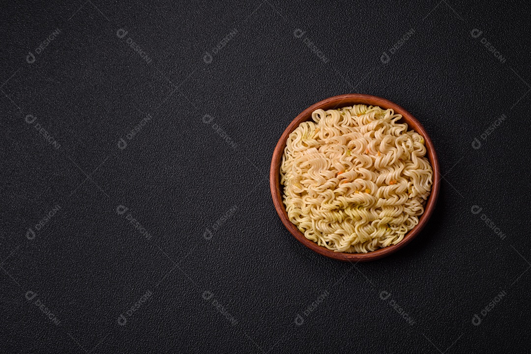 Delicioso macarrão de arroz asiático ou udon com legumes, especiarias e ervas sobre um fundo escuro de concreto