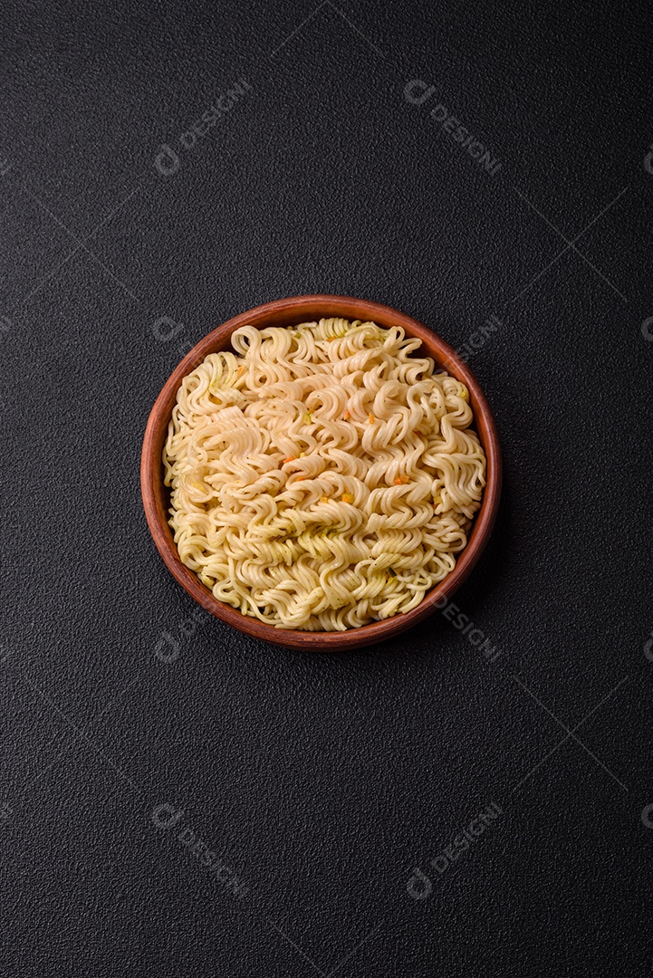 Delicioso macarrão de arroz asiático ou udon com legumes, especiarias e ervas sobre um fundo escuro de concreto