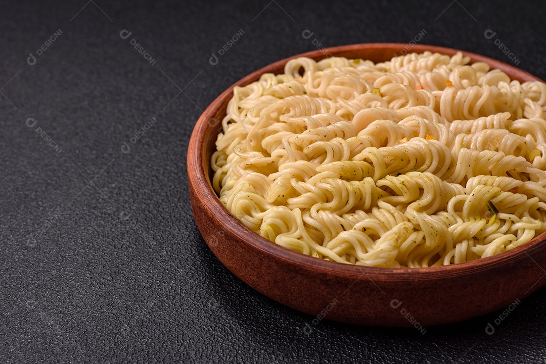 Delicioso macarrão de arroz asiático ou udon com legumes, especiarias e ervas sobre um fundo escuro de concret