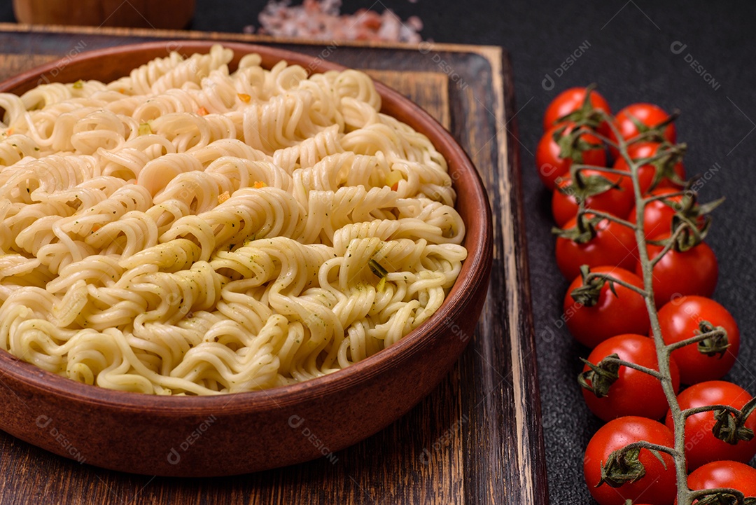 Delicioso macarrão de arroz asiático ou udon com legumes, especiarias e ervas sobre um fundo escuro de concreto