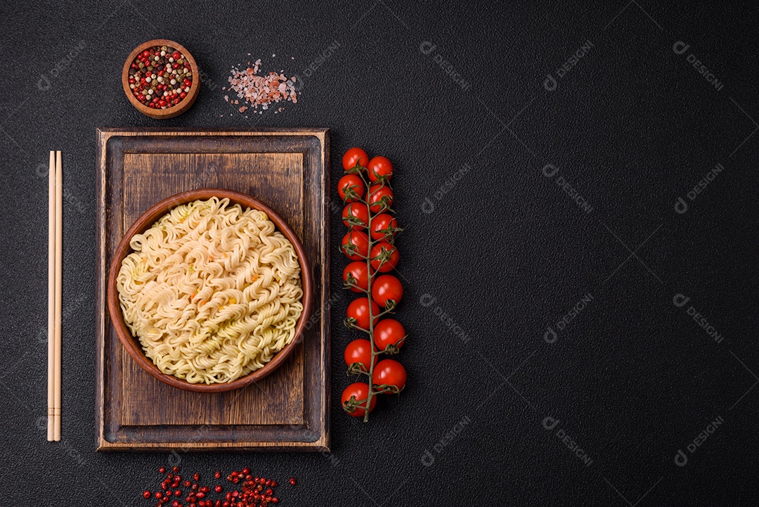 Delicioso macarrão de arroz asiático ou udon com legumes, especiarias e ervas sobre um fundo escuro de concreto