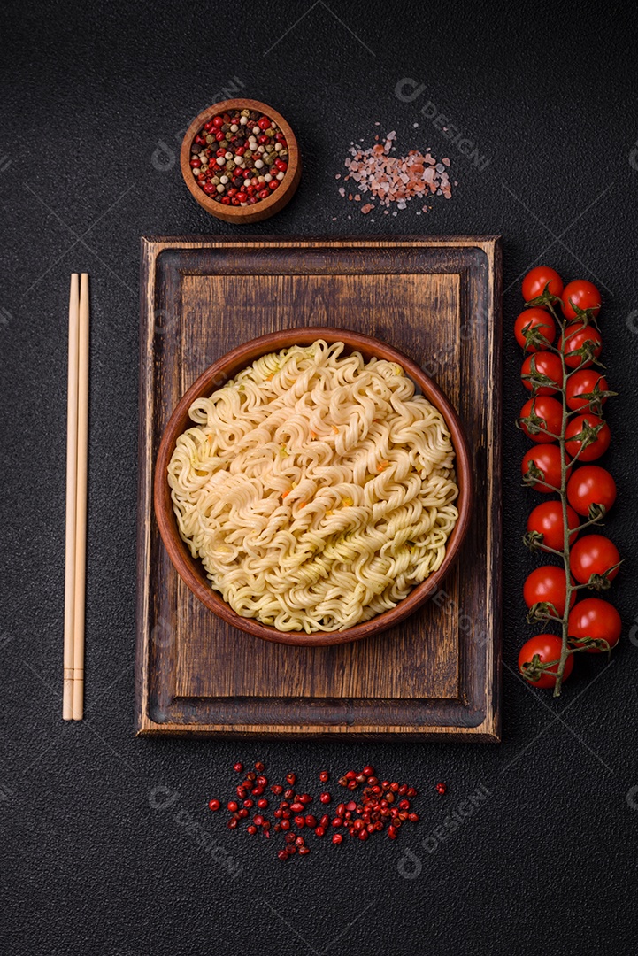Delicioso macarrão de arroz asiático ou udon com legumes, especiarias e ervas sobre um fundo escuro de concreto