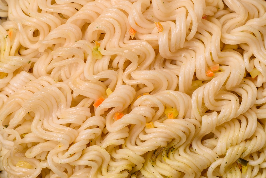 Delicioso macarrão de arroz asiático ou udon com legumes, especiarias e ervas sobre um fundo escuro de concreto