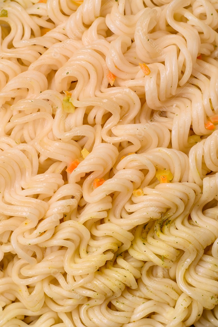 Delicioso macarrão de arroz asiático ou udon com legumes, especiarias e ervas sobre um fundo escuro de concreto