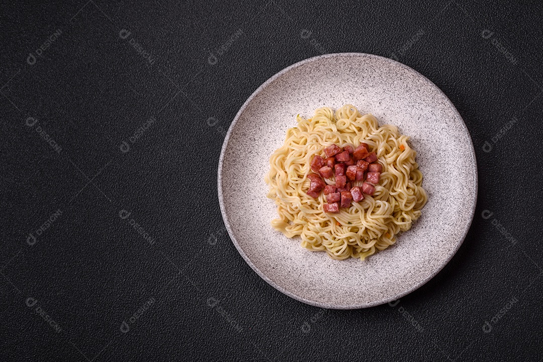 Delicioso macarrão de arroz asiático ou udon com legumes, especiarias e ervas sobre um fundo escuro de concreto