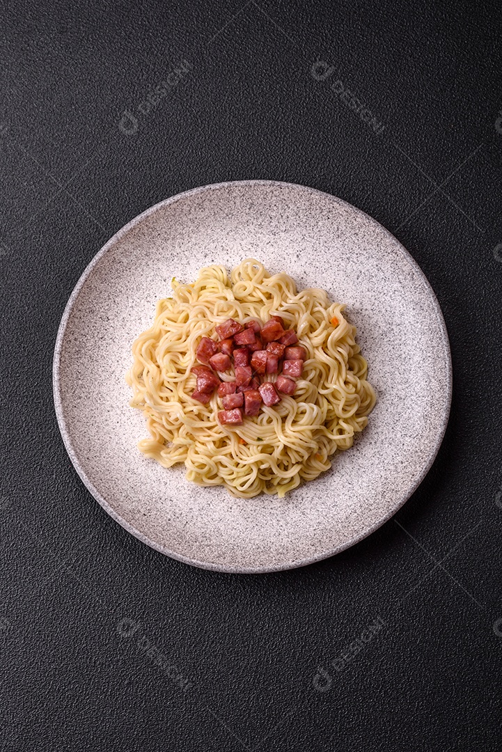 Delicioso macarrão de arroz asiático ou udon com legumes, especiarias e ervas sobre um fundo escuro de concreto