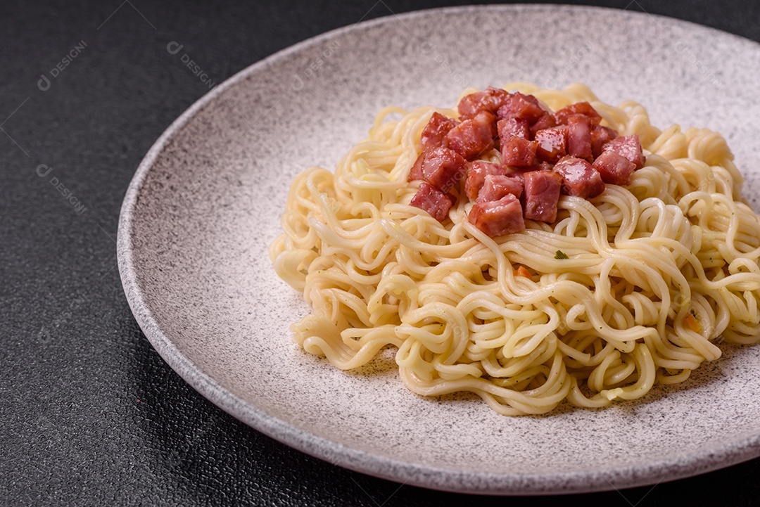 Delicioso macarrão de arroz asiático ou udon com legumes, especiarias e ervas sobre um fundo escuro de concreto