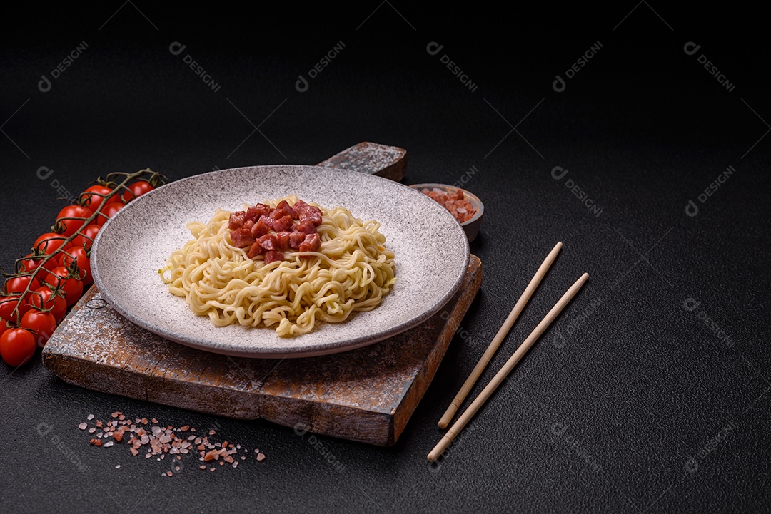 Delicioso macarrão de arroz asiático ou udon com legumes, especiarias e ervas sobre um fundo escuro de concreto