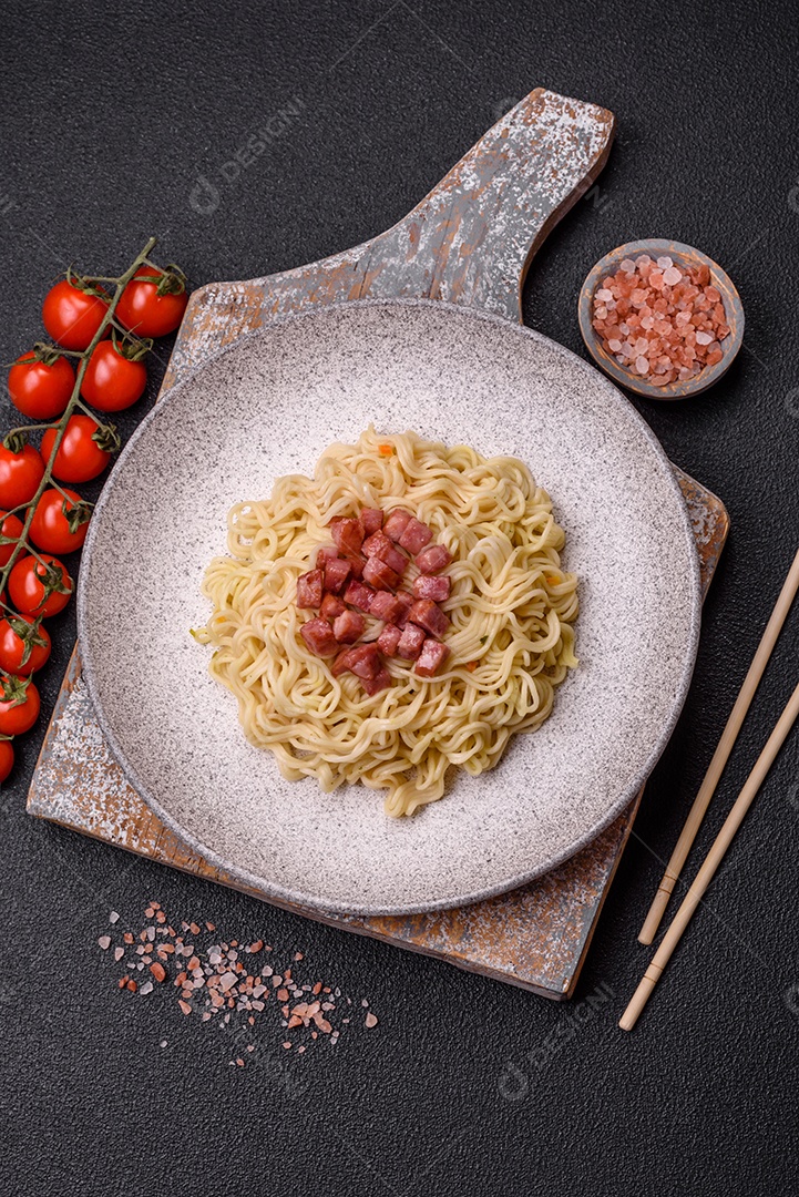 Delicioso macarrão de arroz asiático ou udon com legumes, especiarias e ervas sobre um fundo escuro de concreto