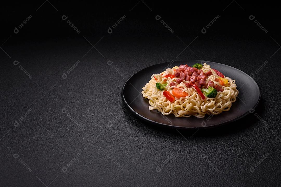 Delicioso macarrão de arroz asiático ou udon com legumes, especiarias e ervas sobre um fundo escuro de concreto