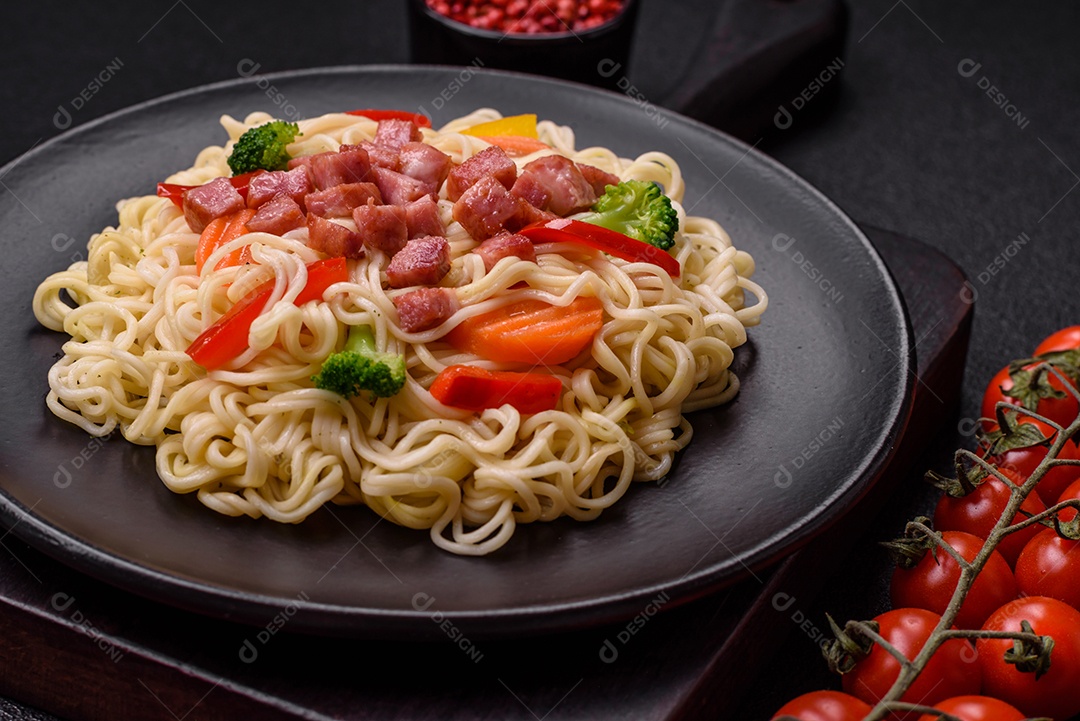 Delicioso macarrão de arroz asiático ou udon com legumes, especiarias e ervas sobre um fundo escuro de concreto