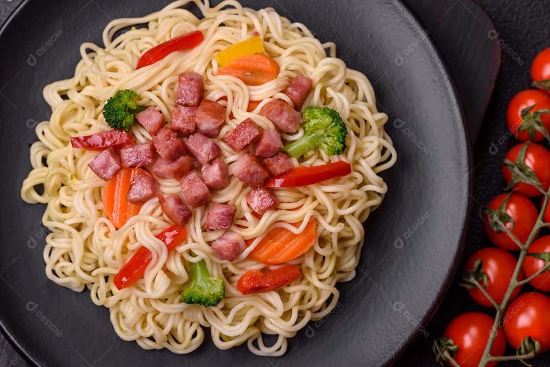 Delicioso macarrão de arroz asiático ou udon com legumes, especiarias e ervas sobre um fundo escuro de concreto