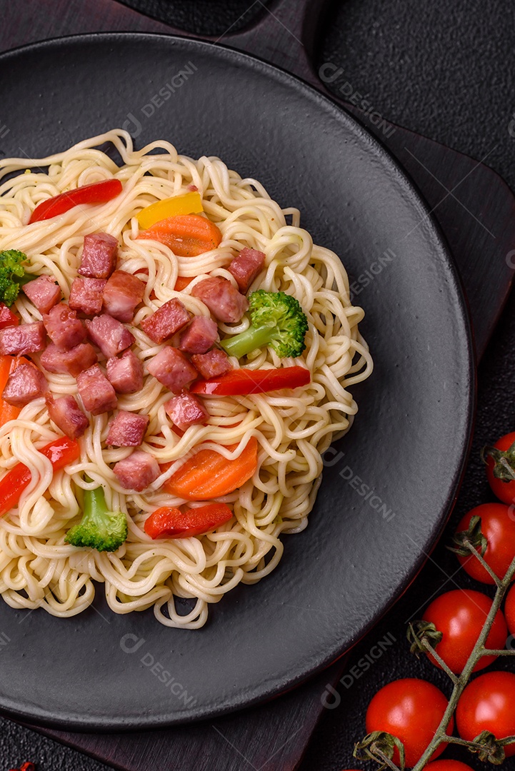 Delicioso macarrão de arroz asiático ou udon com legumes, especiarias e ervas sobre um fundo escuro de concreto