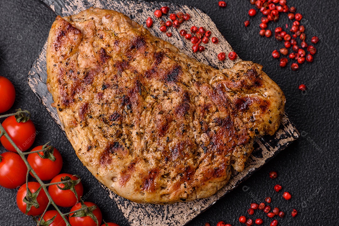 Delicioso bife de porco suculento com sal, especiarias e ervas sobre um fundo escuro de concreto
