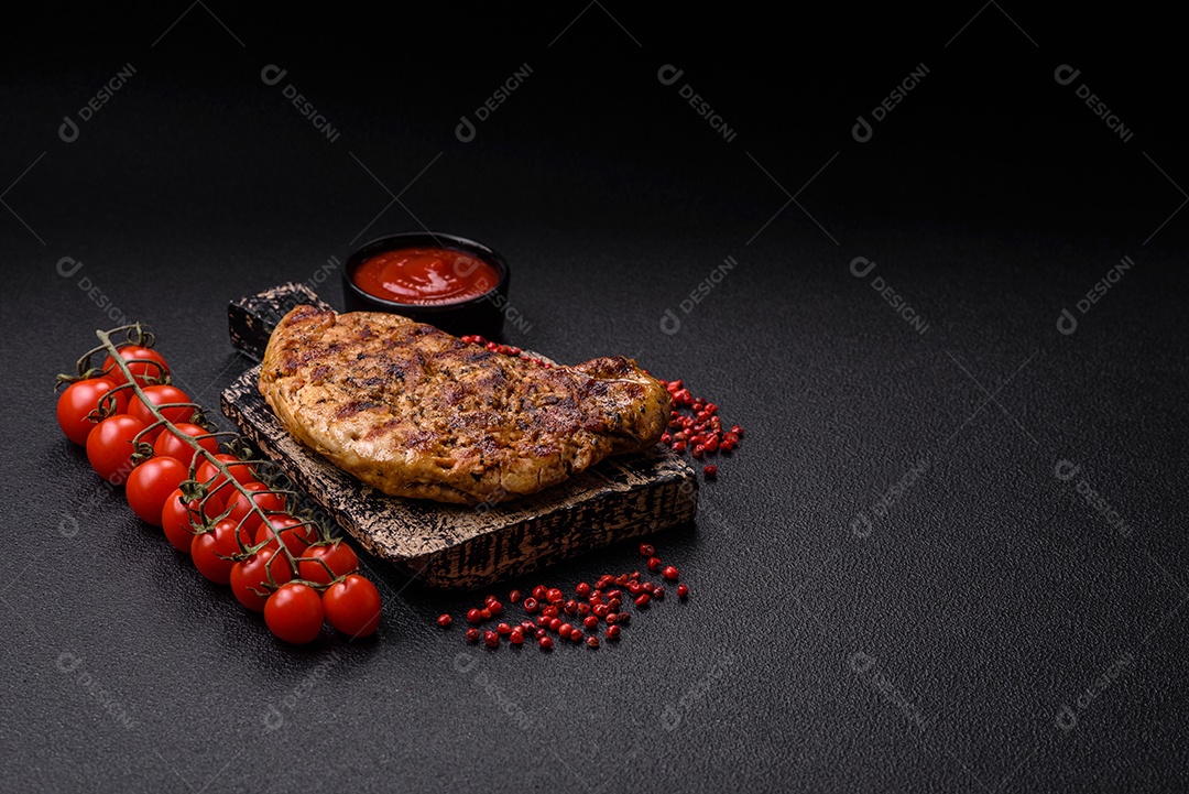 Delicioso bife de porco suculento com sal, especiarias e ervas sobre um fundo escuro de concreto